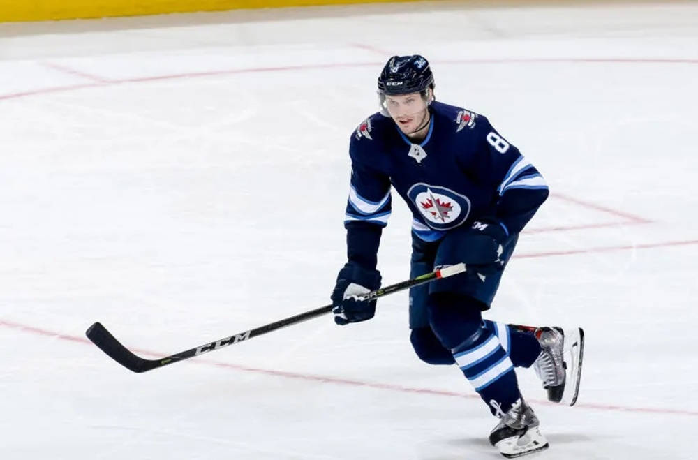 Jacob Trouba Gliding On Ice With Raised Hockey Stick Background