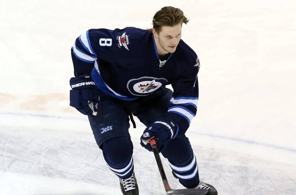 Jacob Trouba Gliding On Ice Without Helmet While Raising Hockey Stick Background