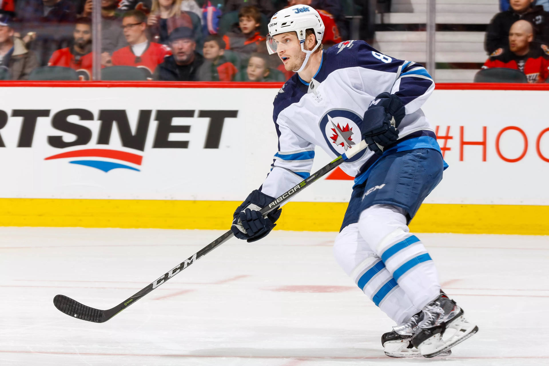 Jacob Trouba Holding Hockey Stick While Leaning To The Right With Mouth Open Background