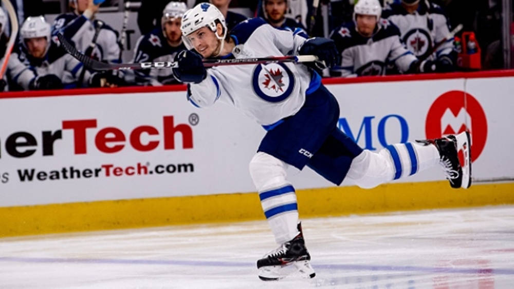 Jacob Trouba Swinging Hockey Stick With Right Leg Raised At The Back Background