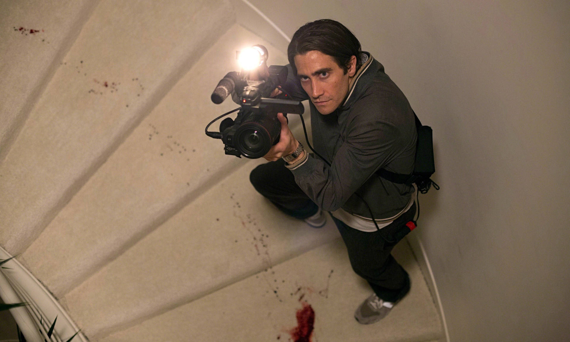Jake Gyllenhaal Holding A Camera Background