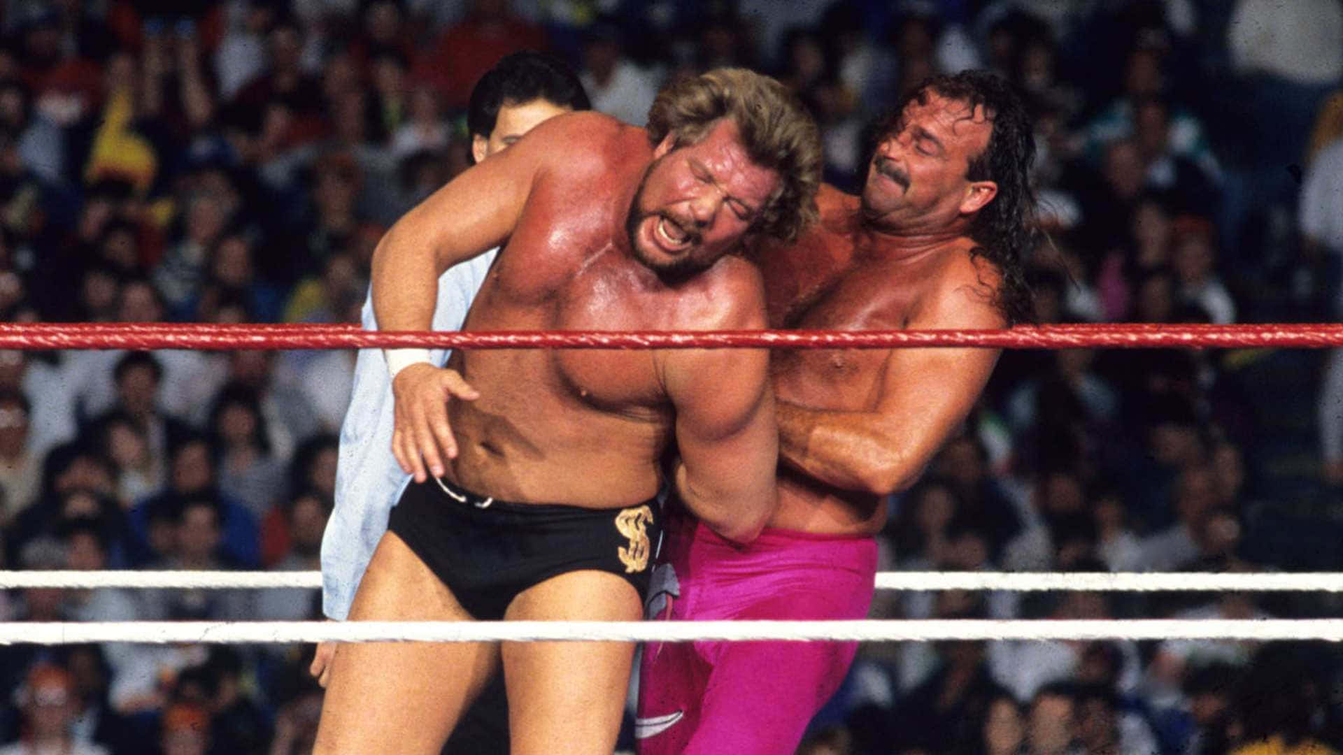 Jake Roberts Holding Ted Dibiase In A Rear Arm Lock Background