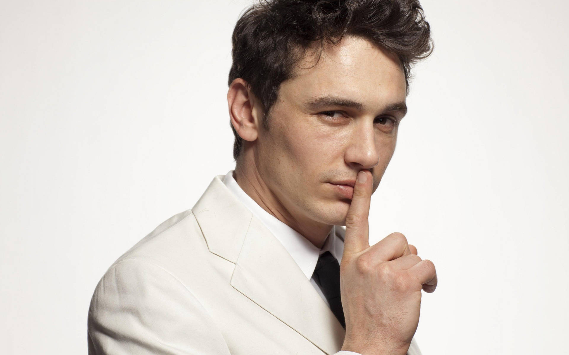 James Franco In White Suit Making A Silence Gesture