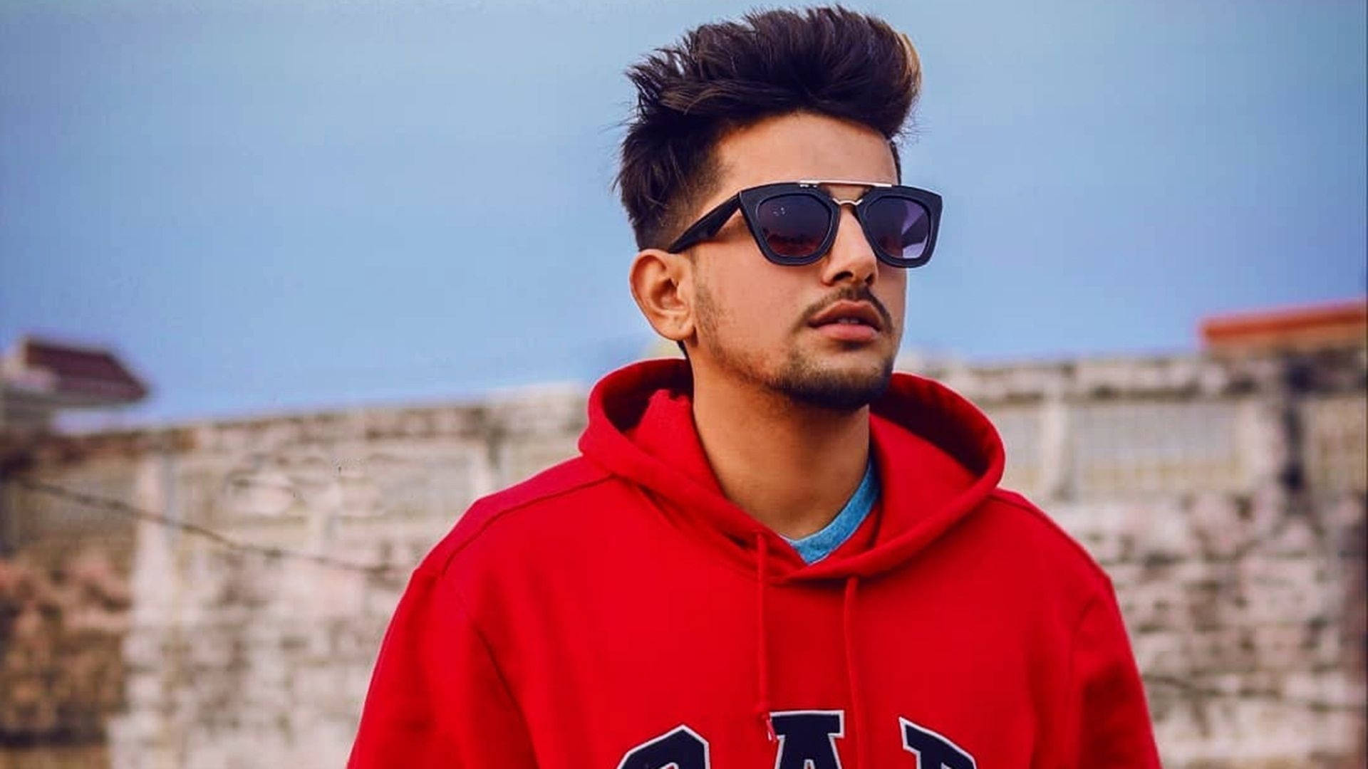 Jass Manak Stylishly Posing In Trendy Red Hoodie. Background