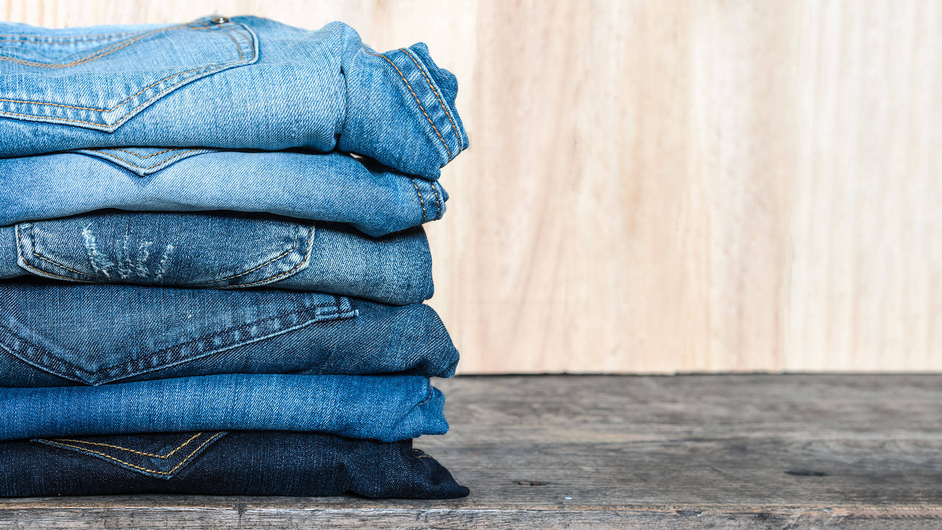 Jeans Stacked On A Wooden Platform Background