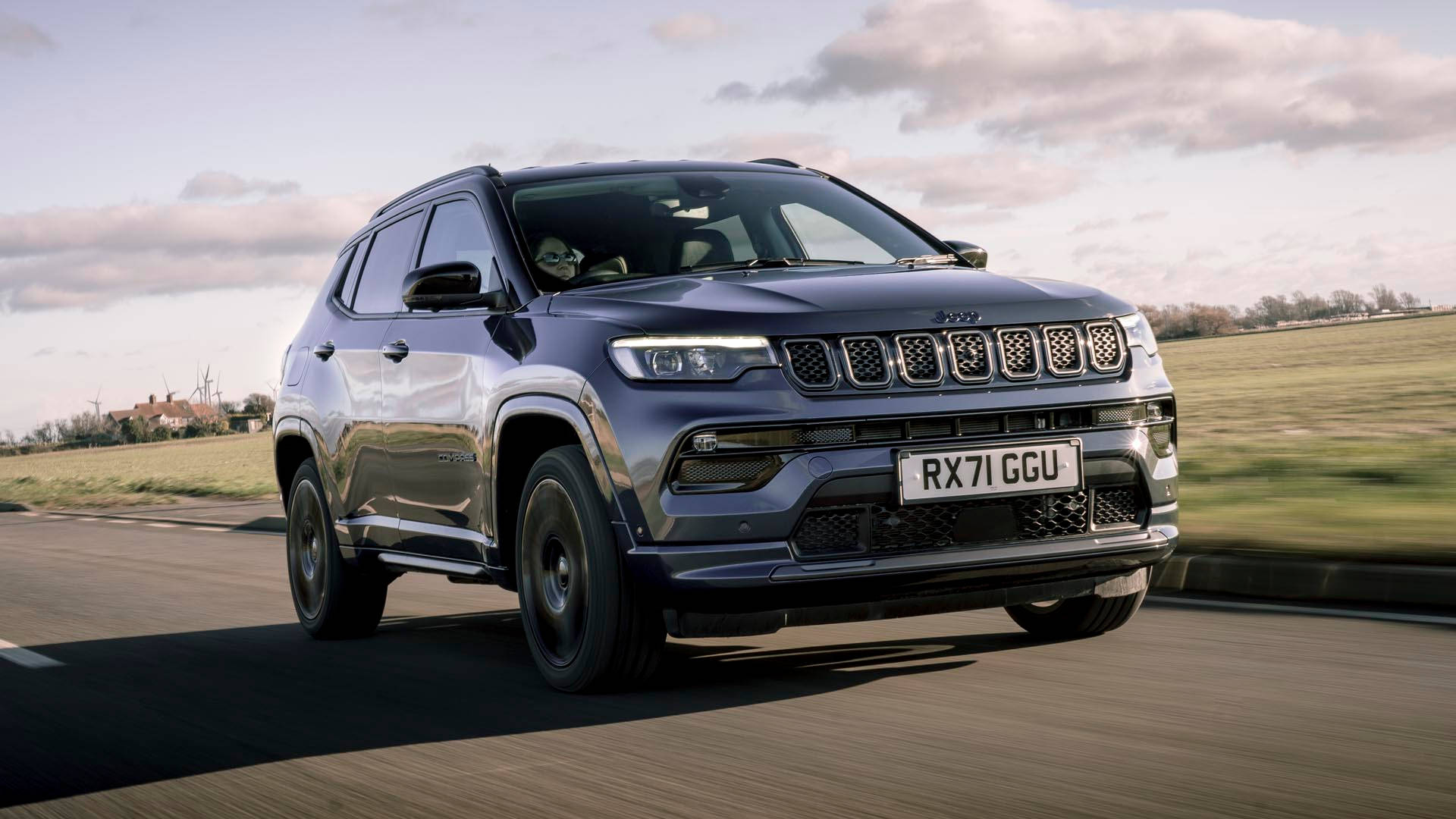 Jeep Compass On The Road Under Clouds Background