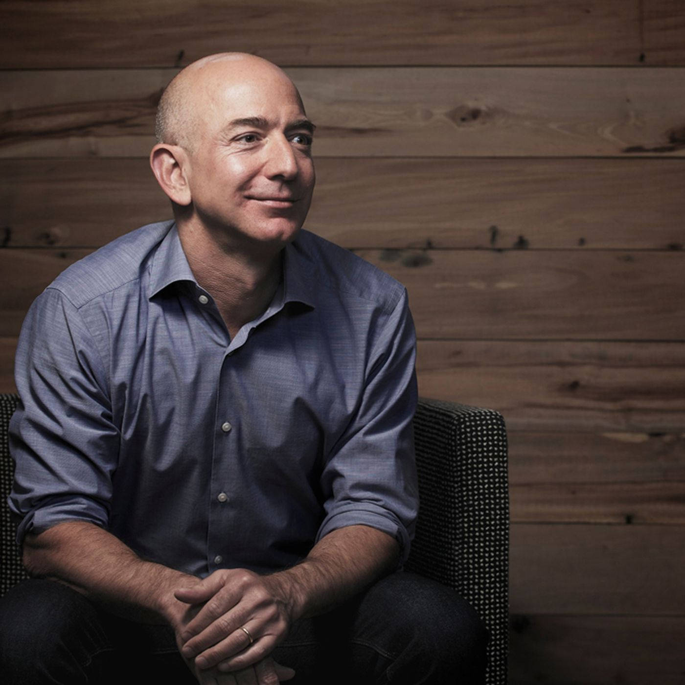 Jeff Bezos Relaxing Against A Wooden Background