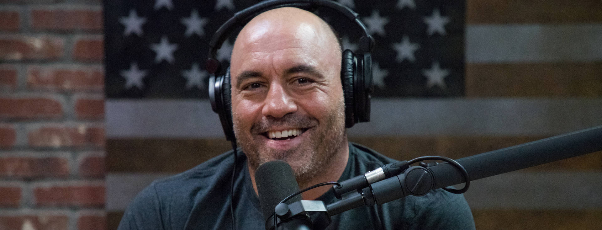 Joe Rogan Smiling On Show Background