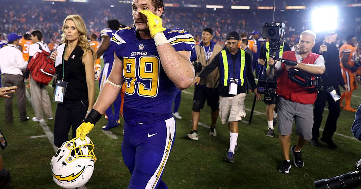 Joey Bosa Fiercely Fighting On The Football Field Background