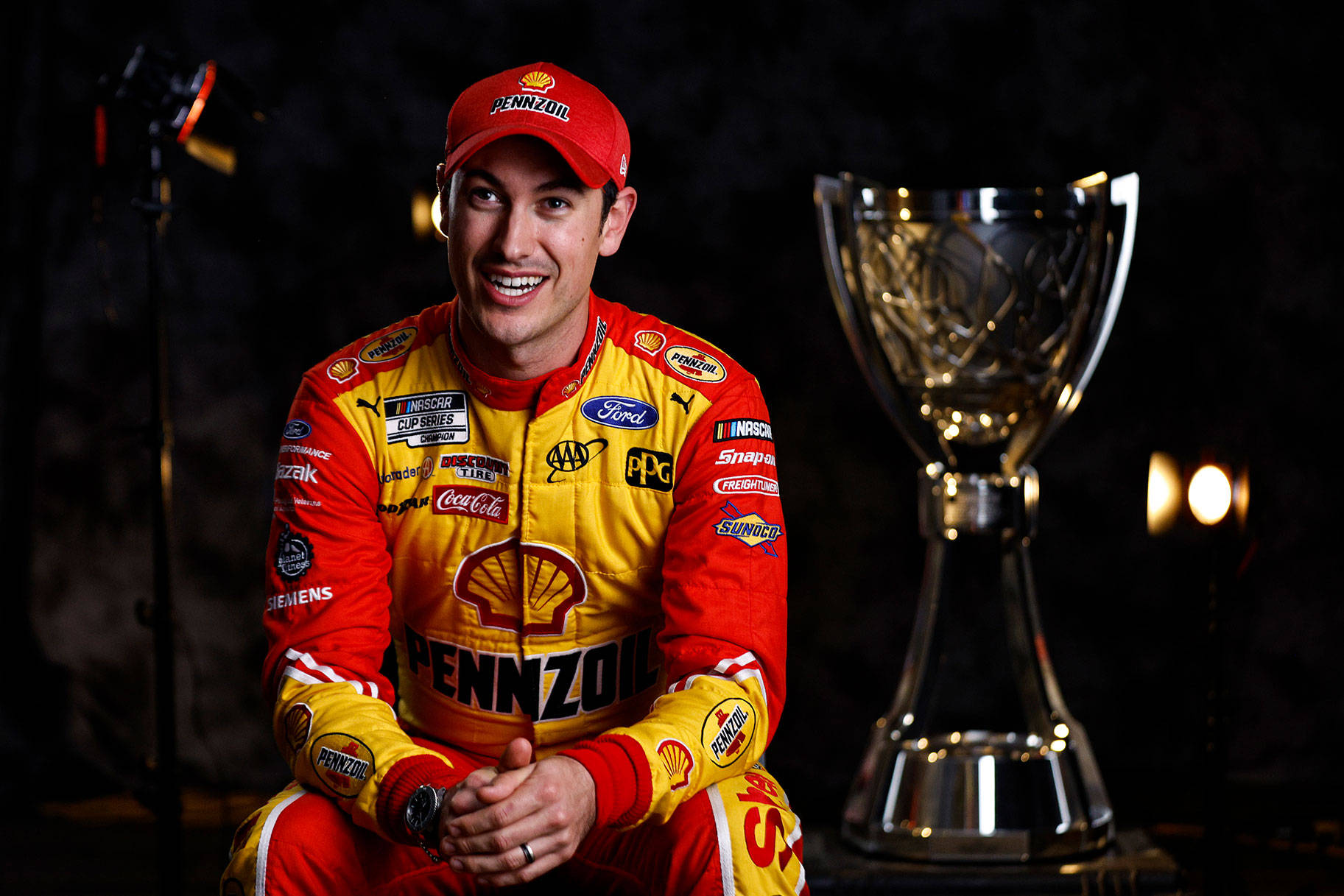 Joey Logano Sitting Beside Blurred Trophy