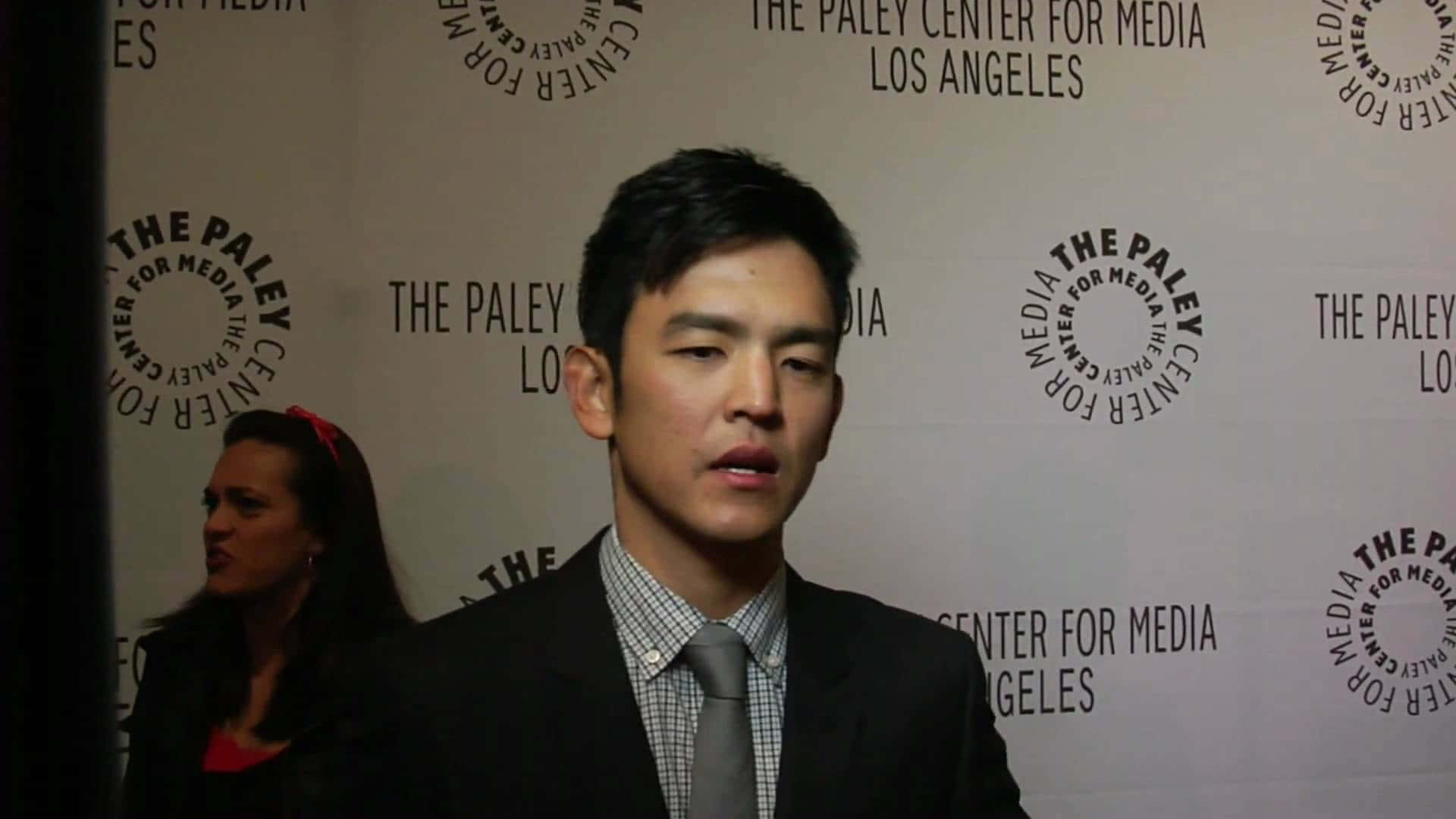 John Cho Posing With A Confident And Charming Smile Background