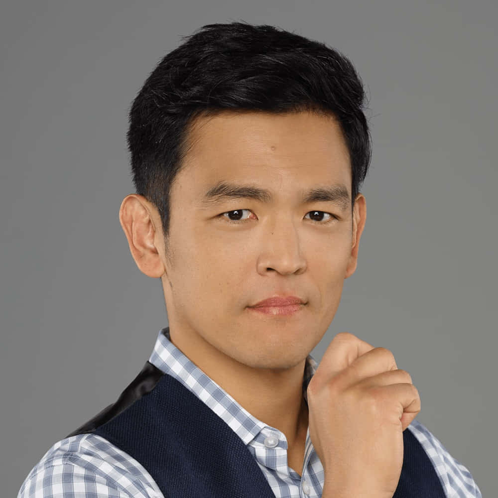 John Cho Striking A Stylish Pose In A Classic Suit. Background