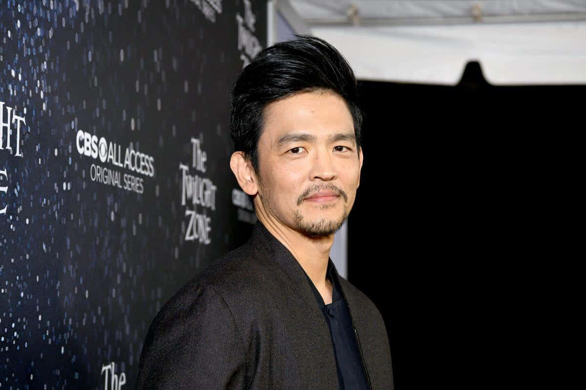 John Cho Striking A Stylish Pose In A Photoshoot Background