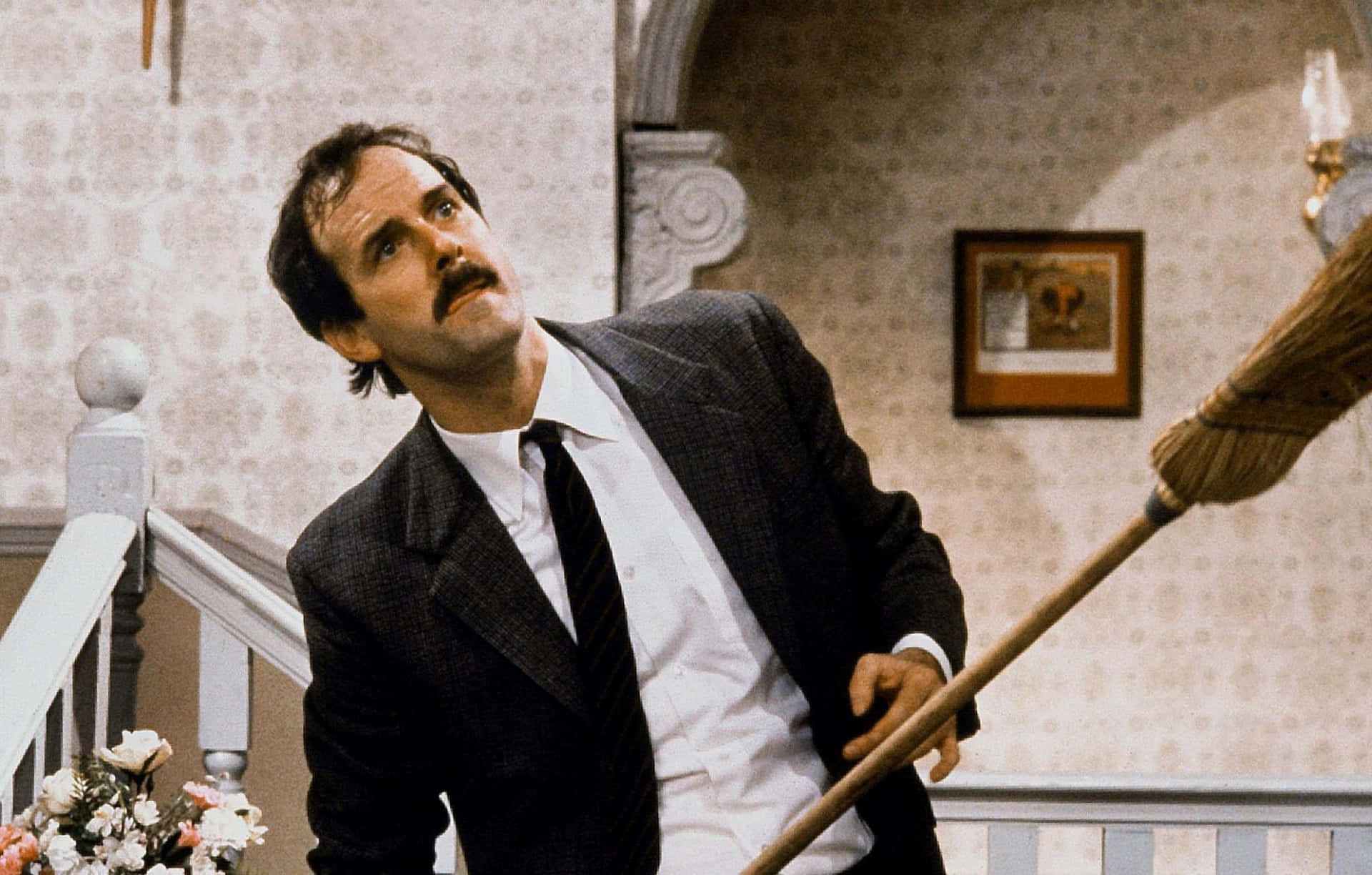 John Cleese With Broom Comedic Scene Background