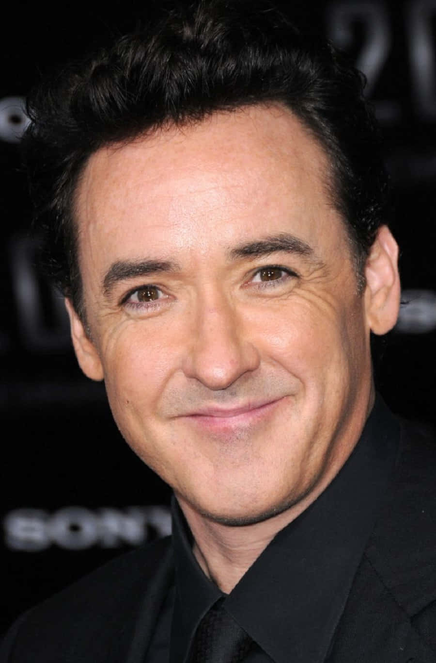John Cusack Posing With A Quirky Expression For A Photoshoot Background