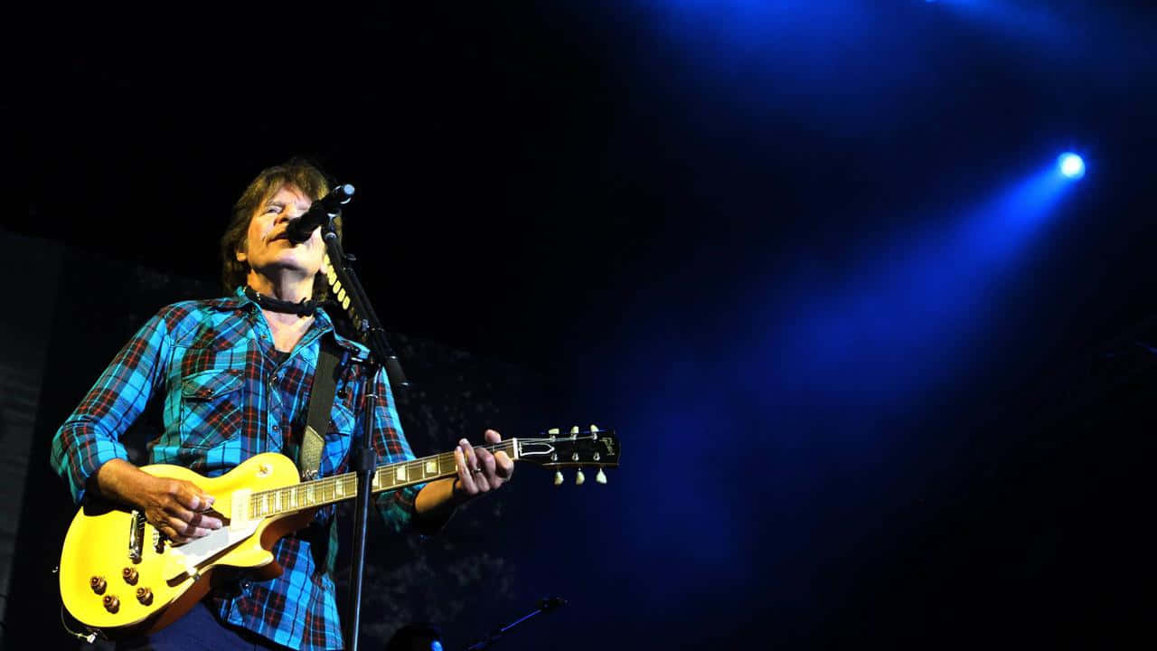 John Fogerty Performing Liveon Stage Background