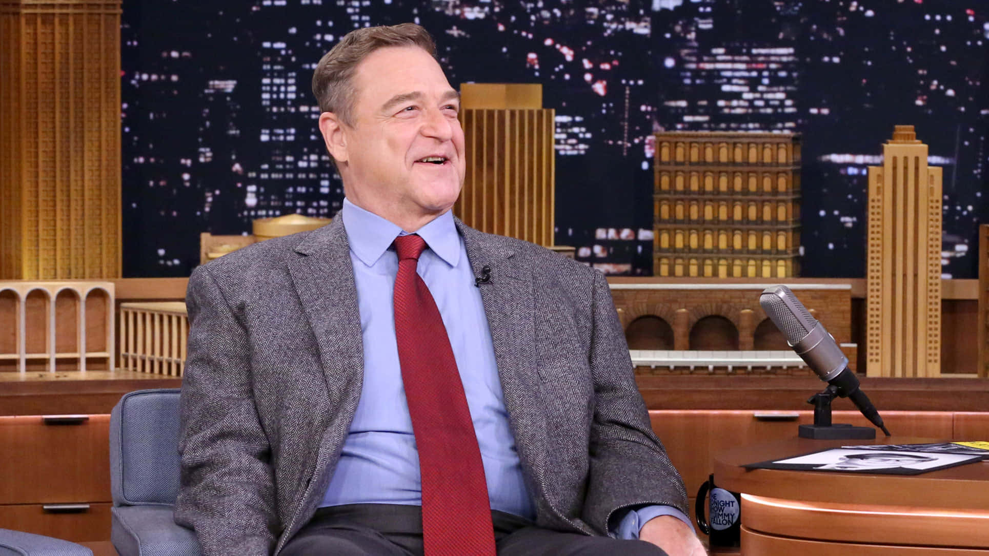 John Goodman Smiling At A Press Event Background