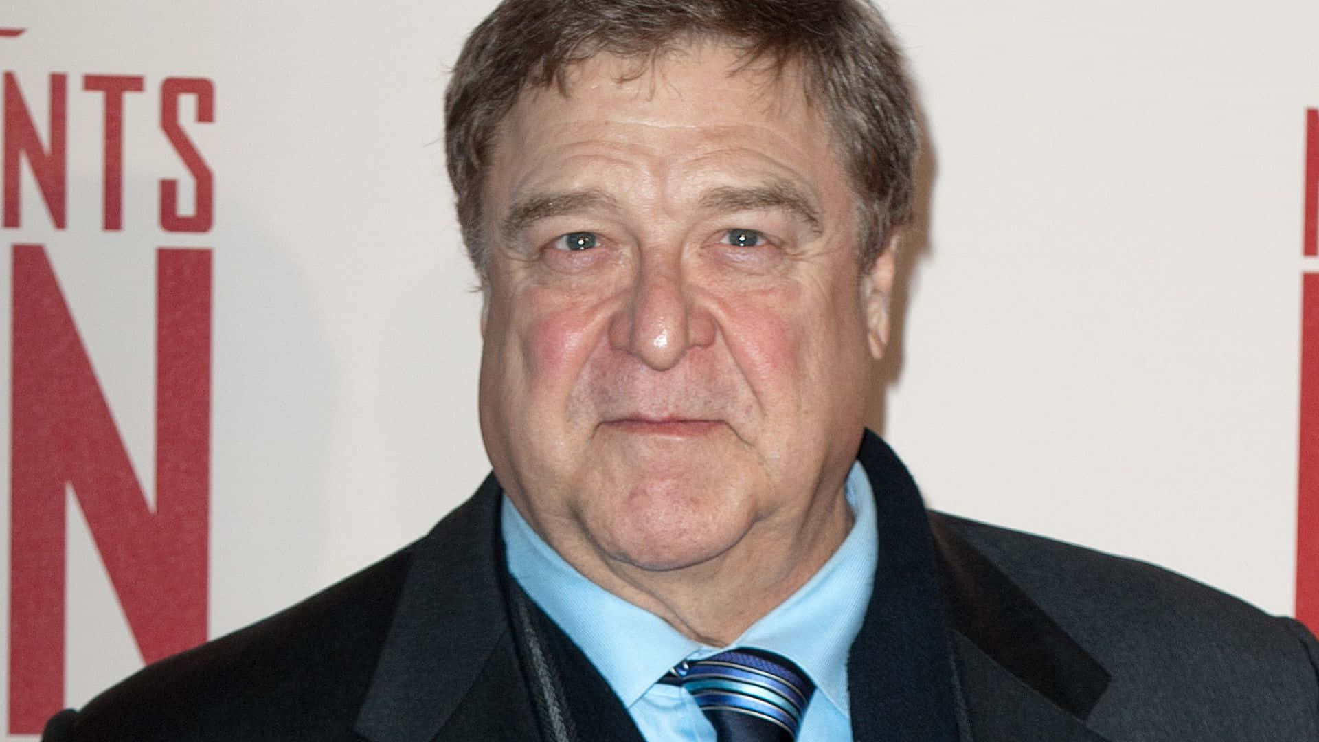 John Goodman Smiling At A Red Carpet Event. Background
