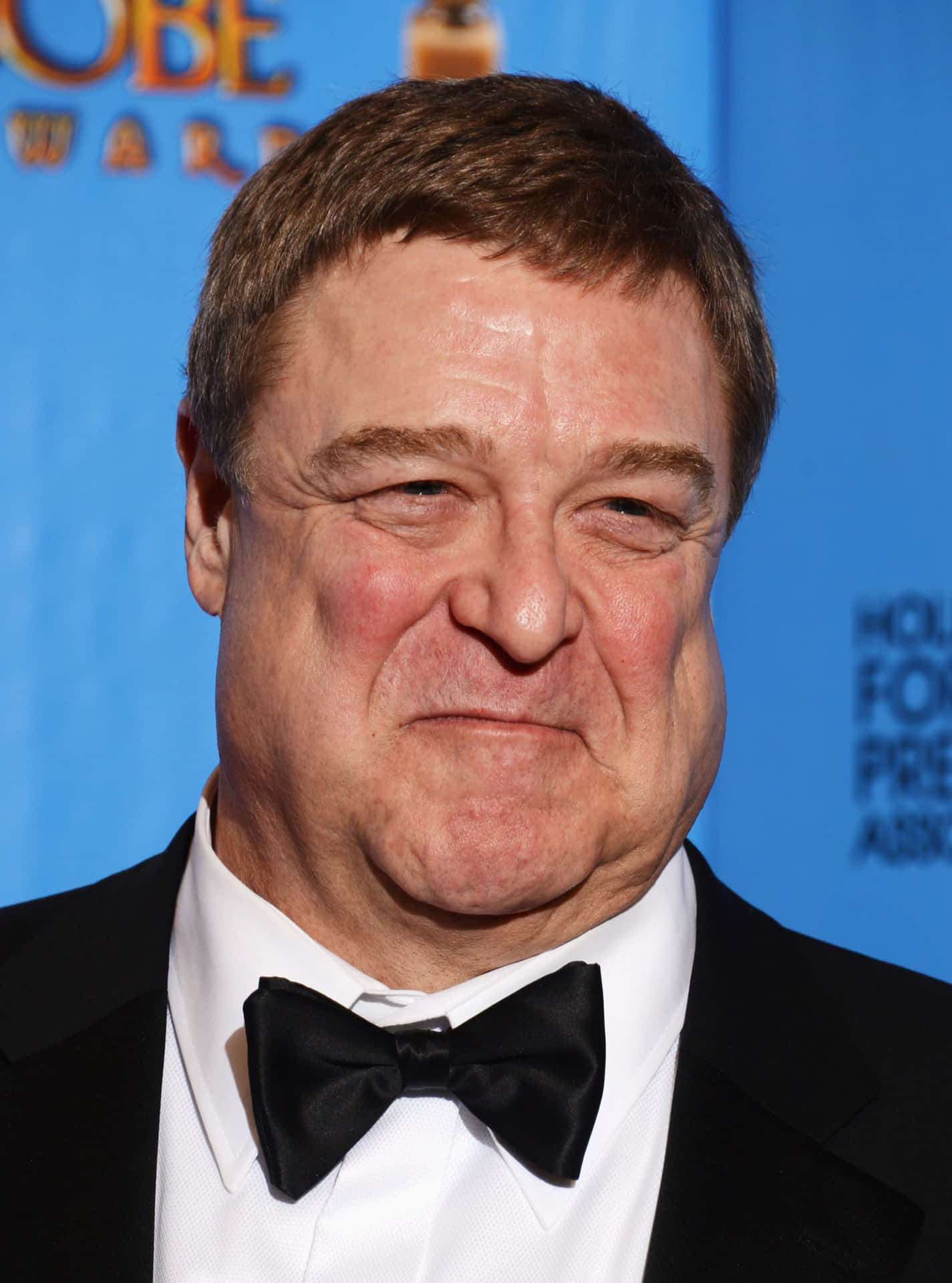 John Goodman Smiling In A Formal Outfit Background