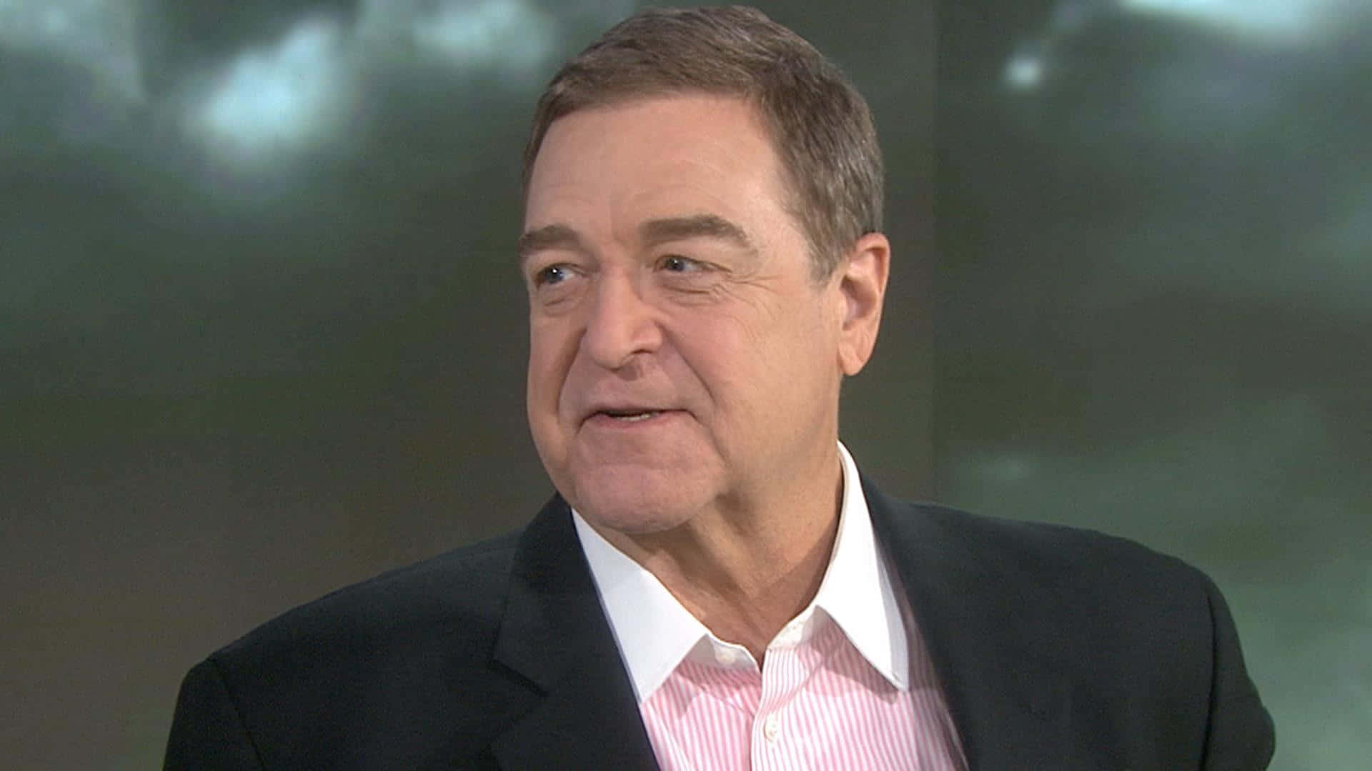 John Goodman Smirking During A Red Carpet Event Background