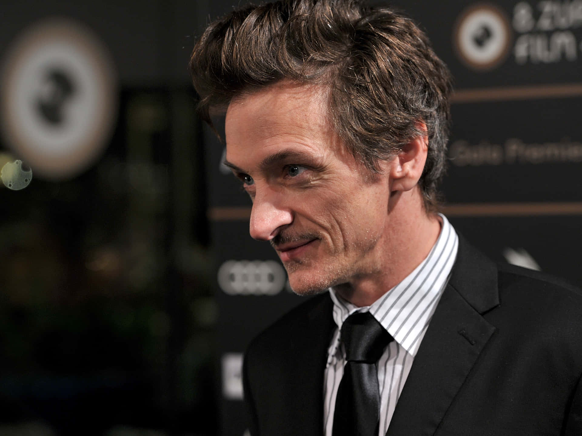 John Hawkes Striking A Pose In A Black Suit Background
