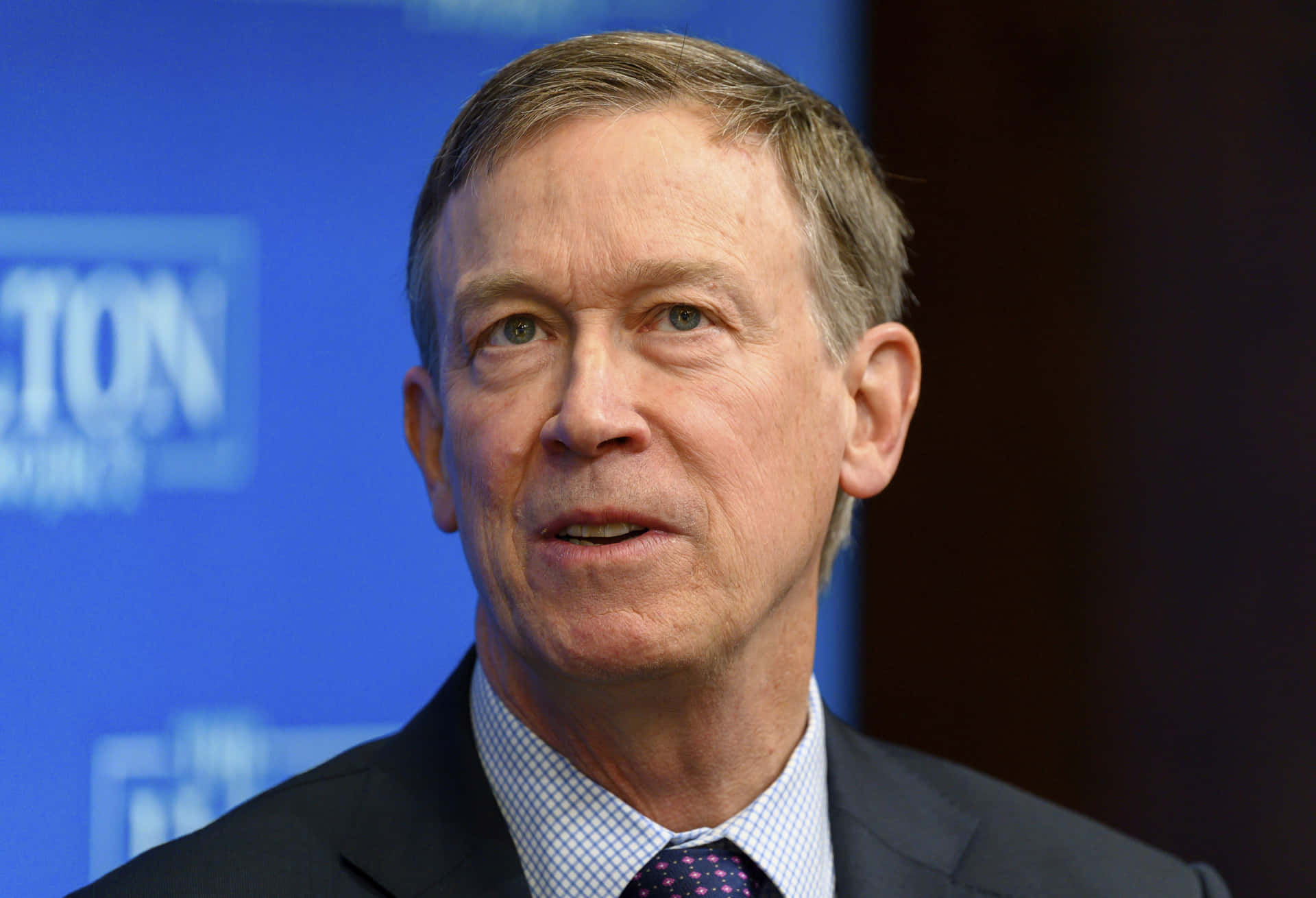 John Hickenlooper Against A Blue And Black Backdrop