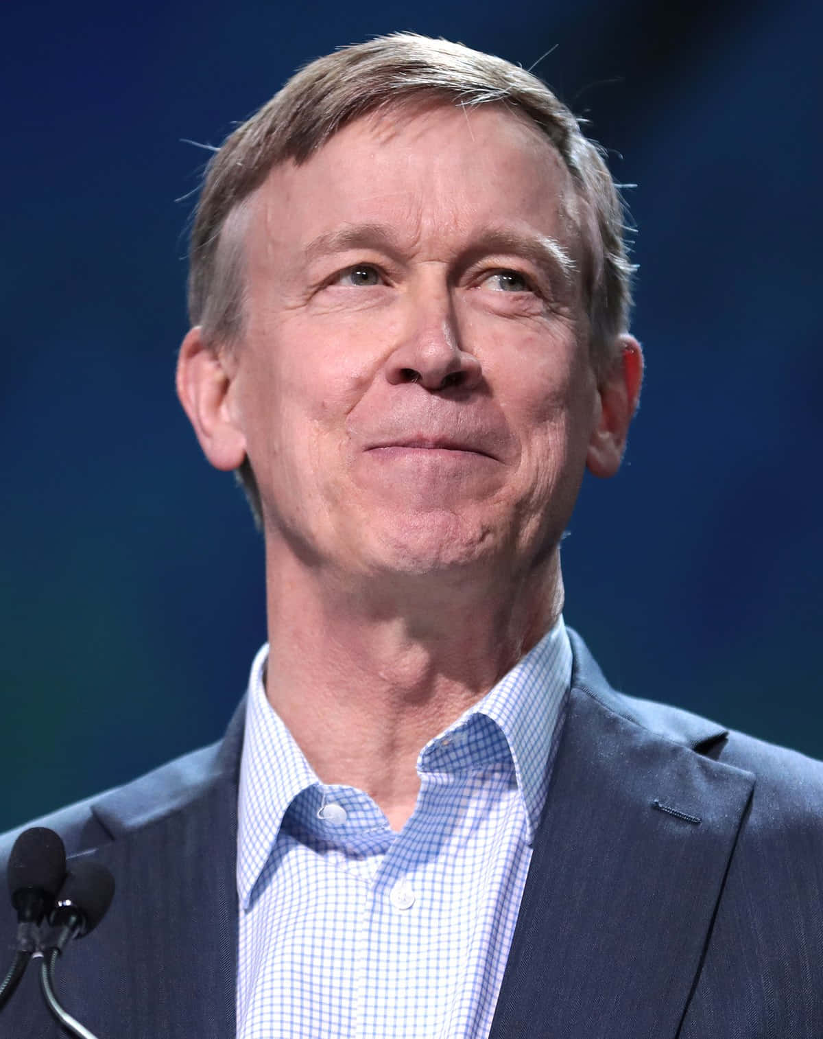 John Hickenlooper Smiling In A Dark Blue Suit Background