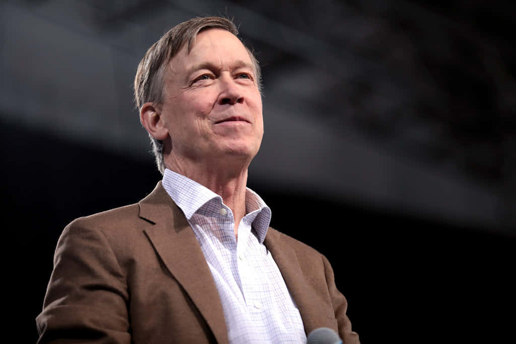 John Hickenlooper With A Black And Gray Backdrop