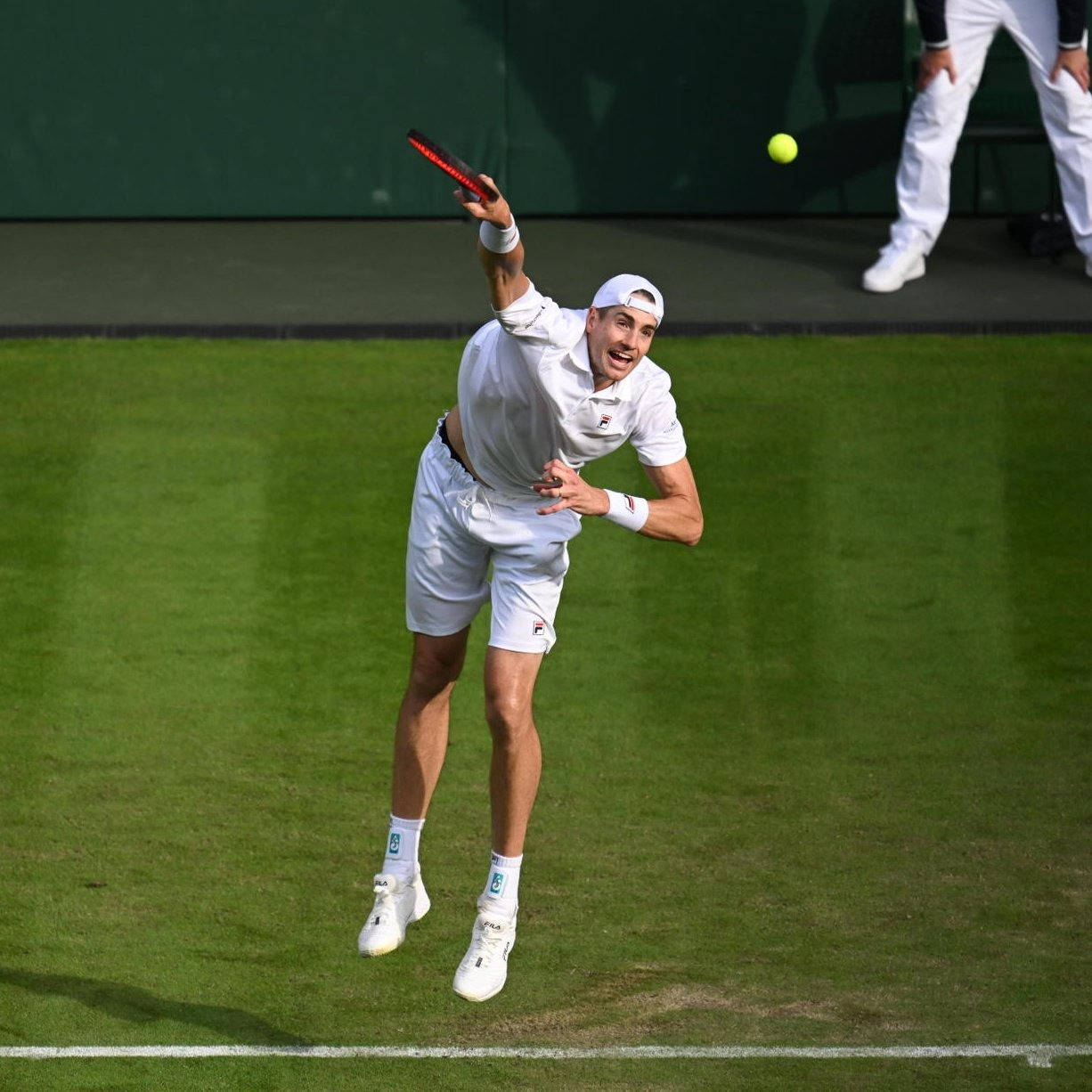 John Isner Exhibiting His Tennis Skills In A Match Background