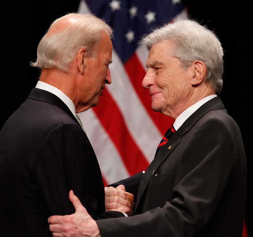 John Warner And Joe Biden With American Flag Background