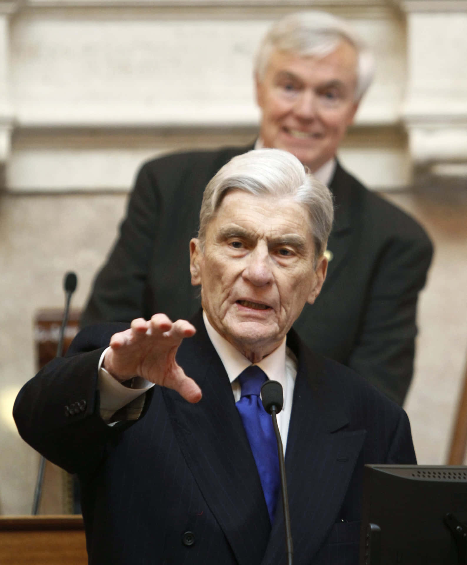 John Warner In Black Suit Raising His Hand Background