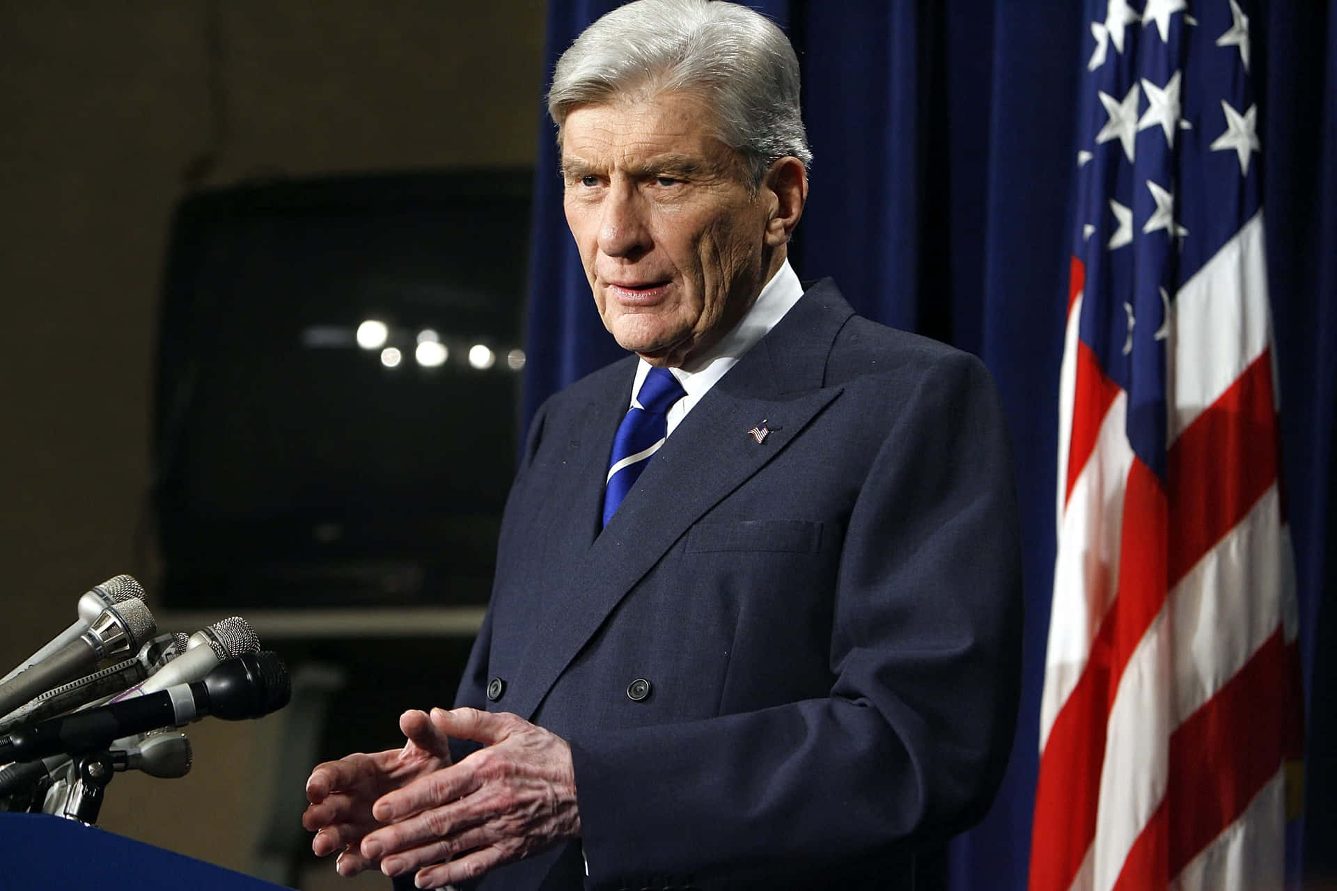 John Warner With Hands Together By The Flag