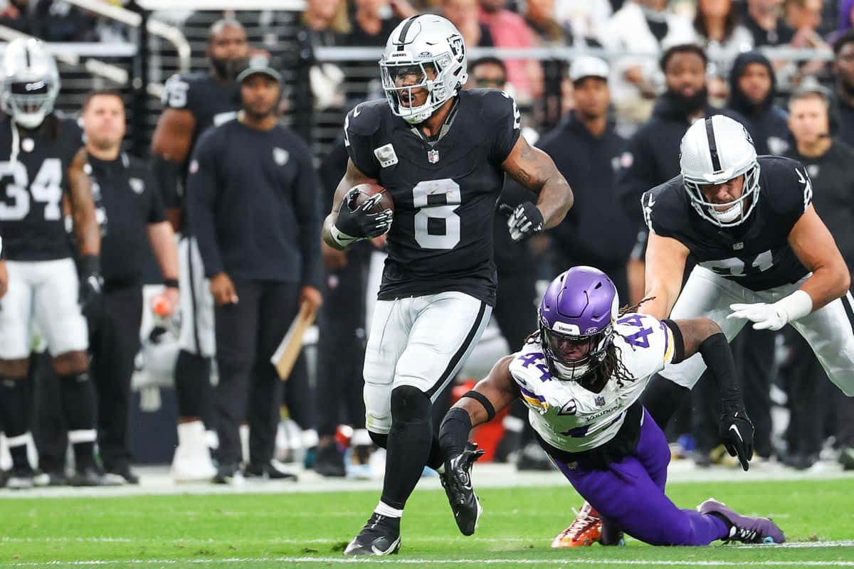 Josh Jacobs Evading Tackle During Game Background