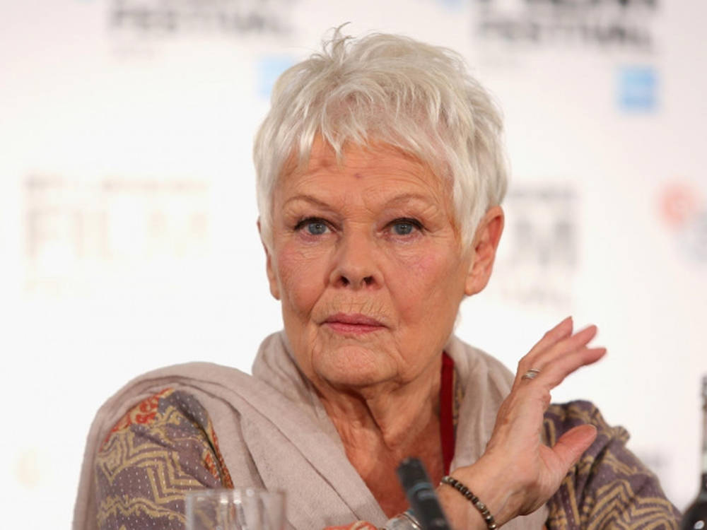 Judi Dench Striking A Pose With A Playful Hand Gesture Background