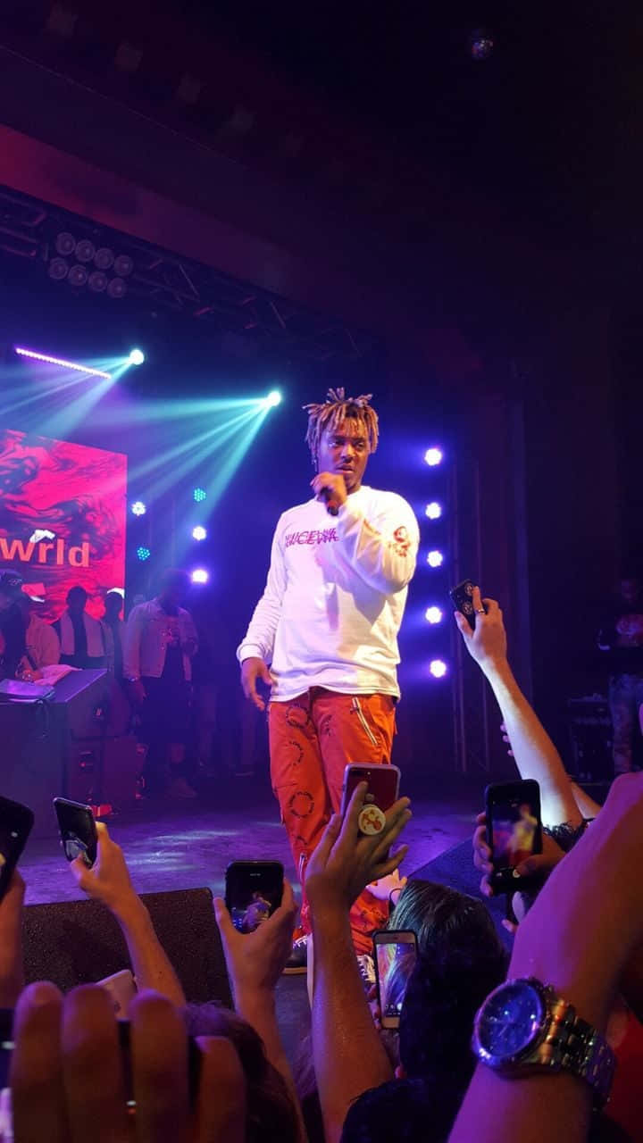 Juice Wrld Standing With His Iconic Skullcandy And Iphone Background