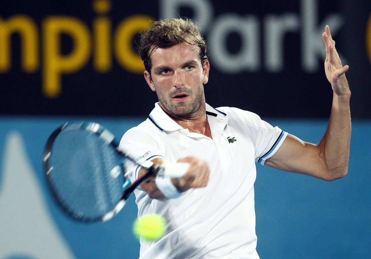 Julien Benneteau In Action, Expertly Launching The Tennis Ball With His Racket Background