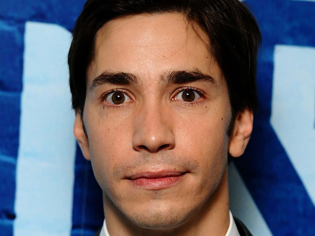 Justin Long Smiling On A Red Background