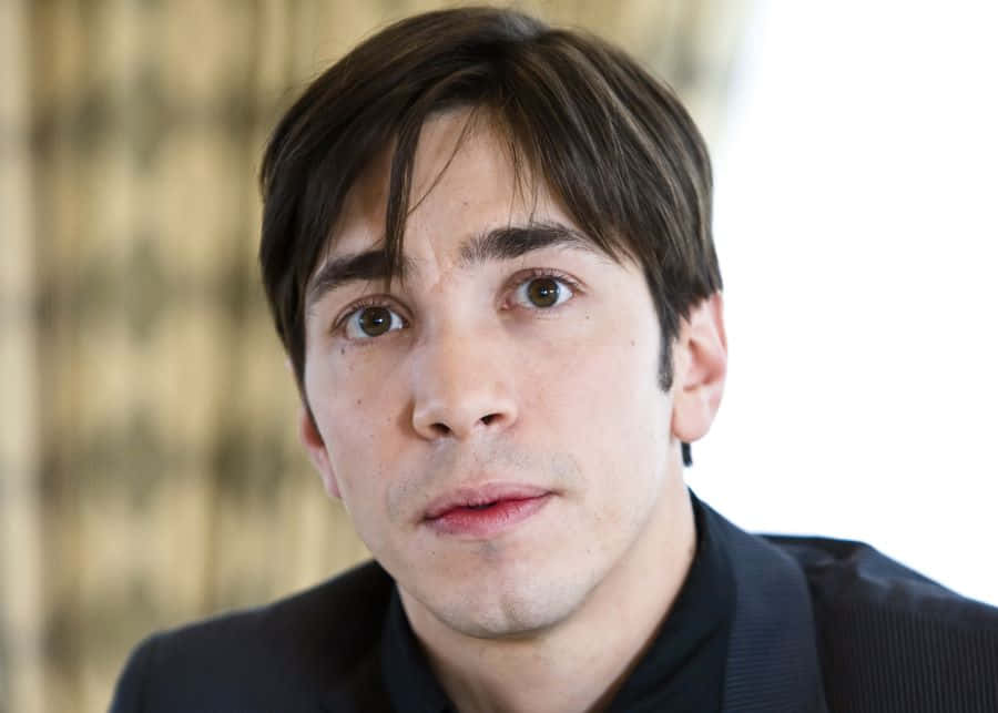 Justin Long Striking A Confident Pose In Style Background