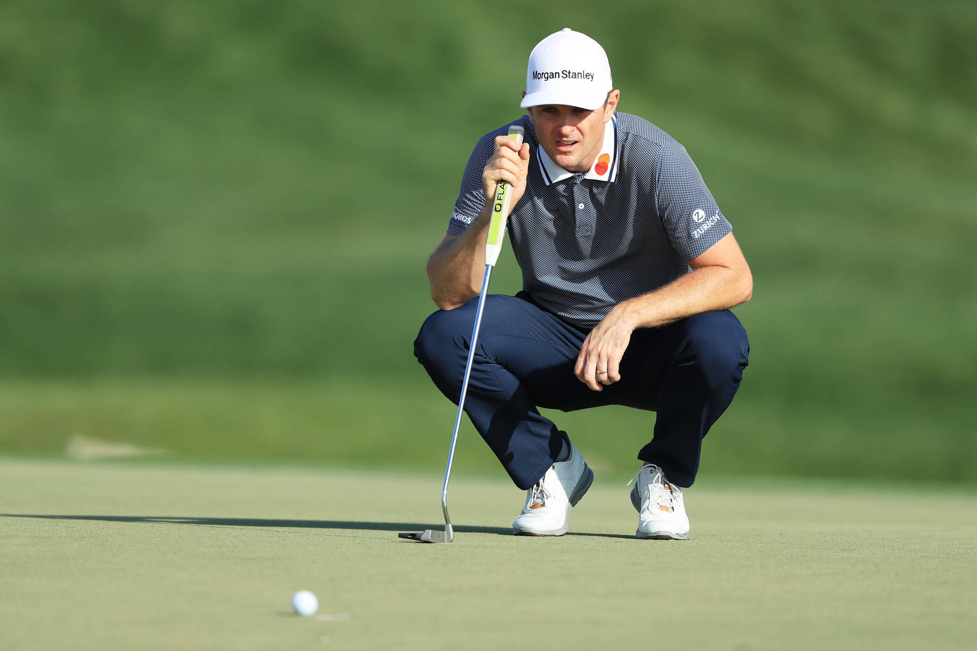 Justin Rose Looking At A Golf Ball While Squatting Background