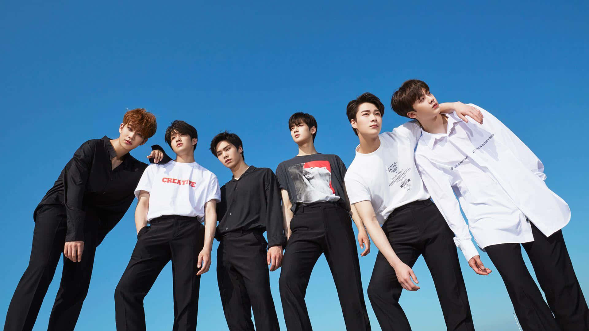 K Pop_ Group_ Astro_ Posing_ Against_ Blue_ Sky Background