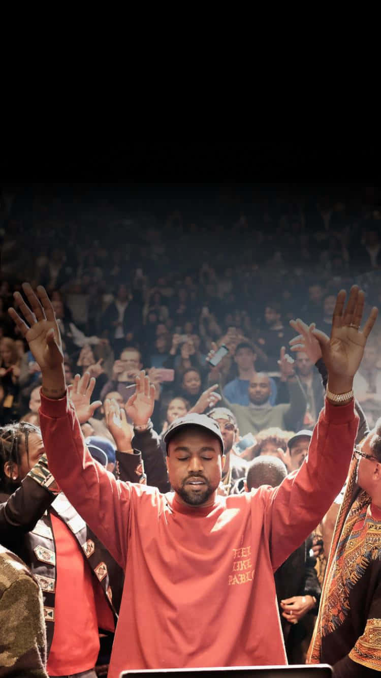 Kanye West At A Concert With His Hands Up Background