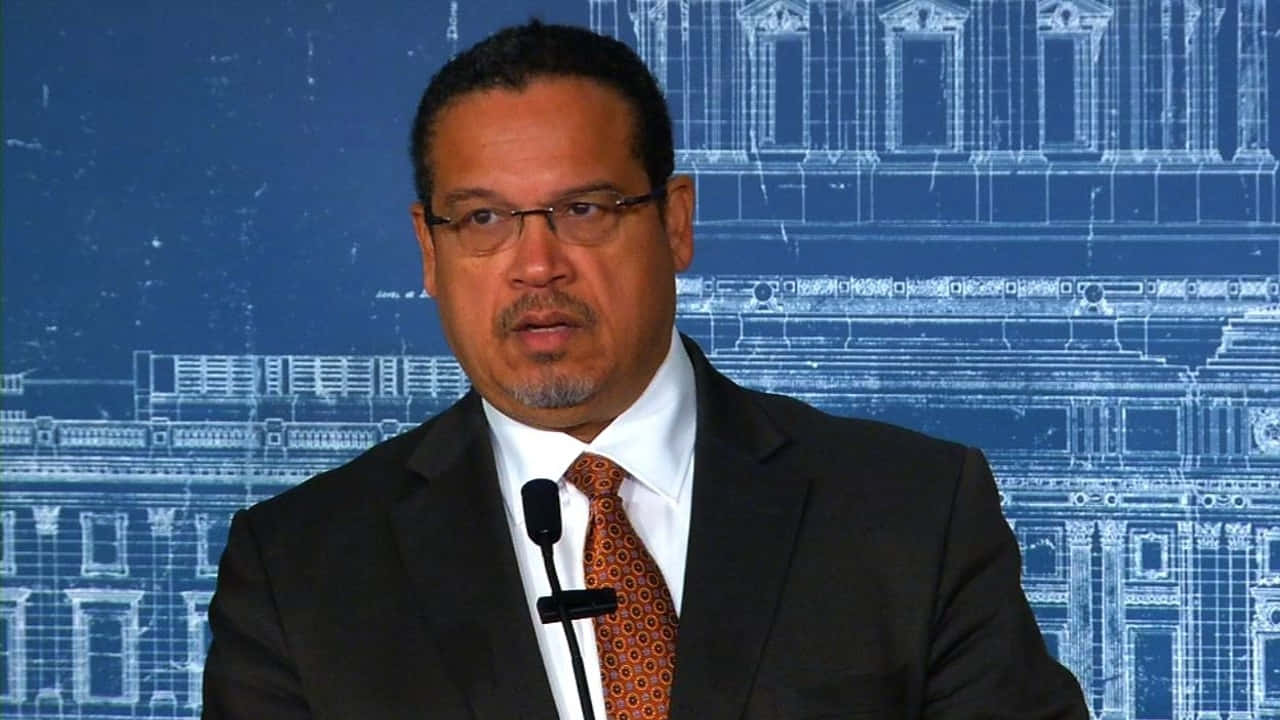 Keith Ellison Holding A Blueprint Against A Blue Background Background