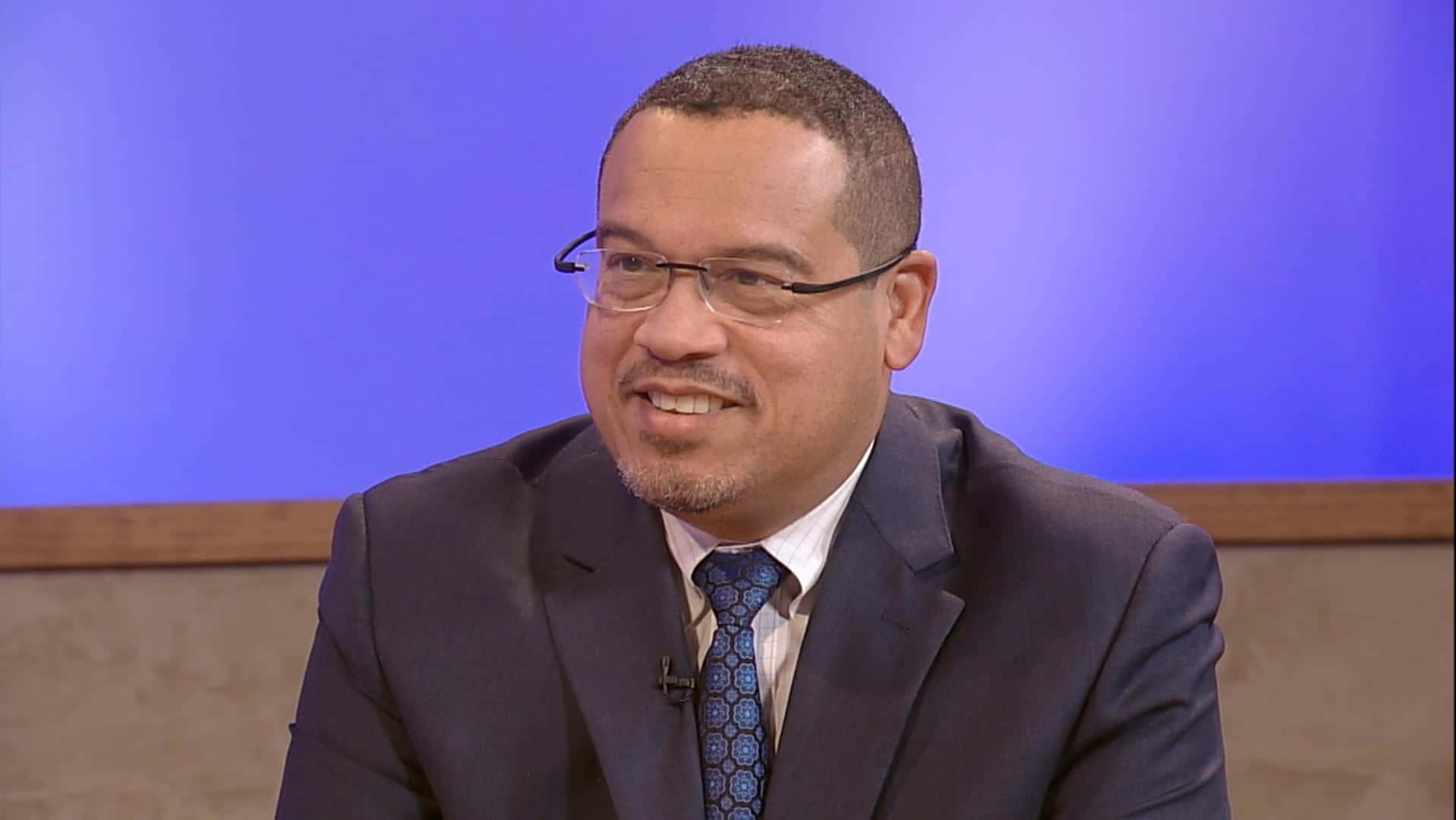 Keith Ellison In Blue And Brown Wall Background