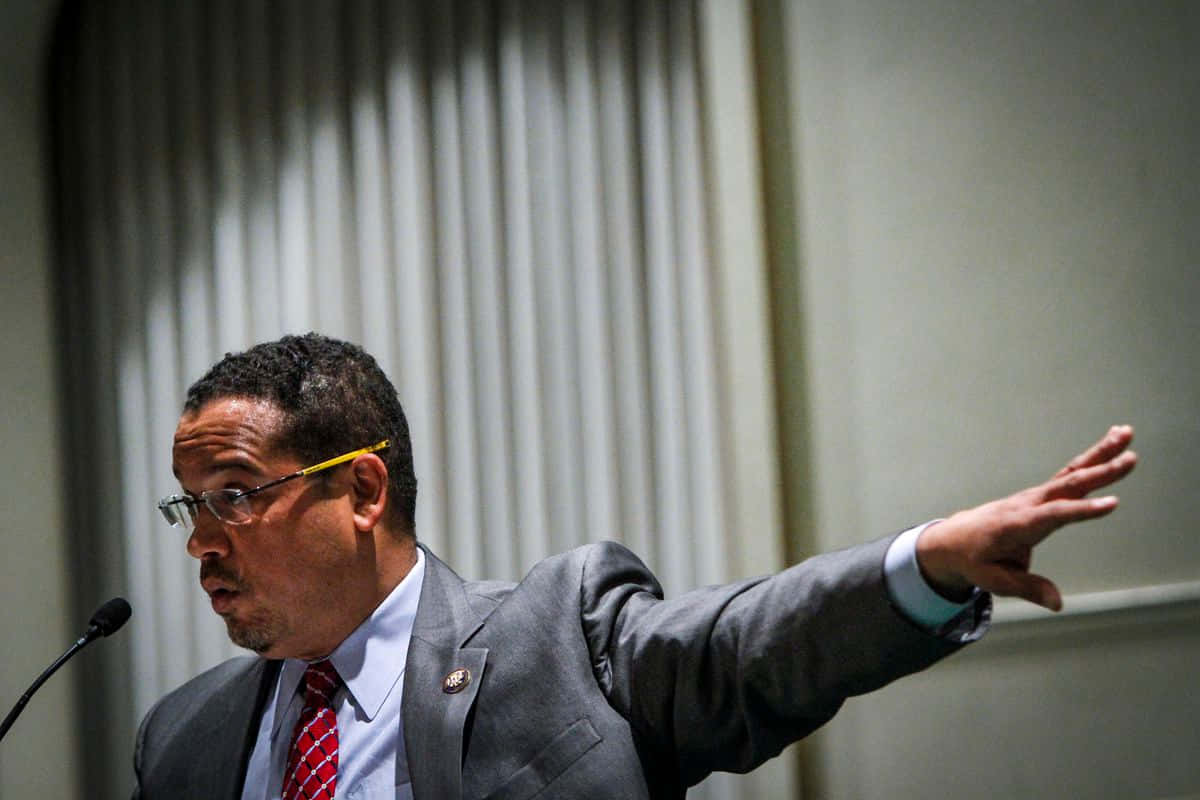 Keith Ellison Reaching To His Side Background