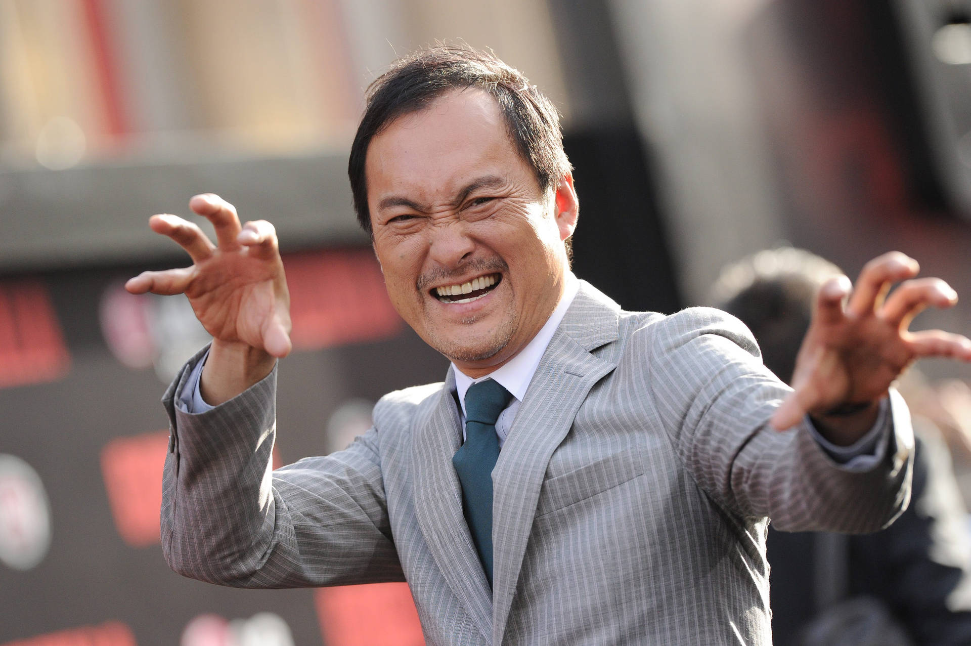 Ken Watanabe Exhibiting A Funny Pose On The Red Carpet Background