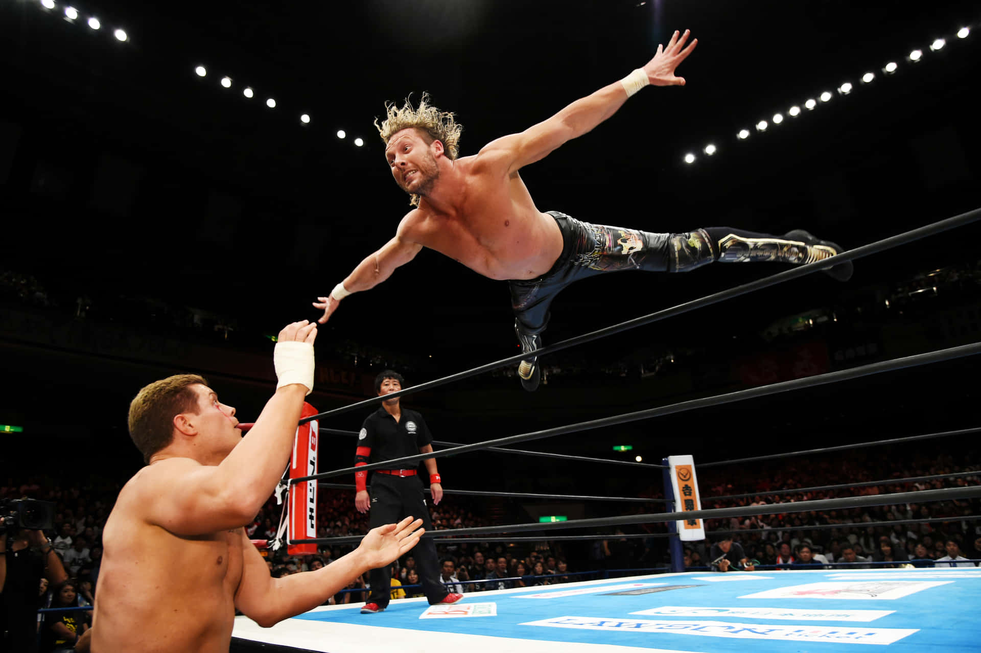 Kenny Omega Swan Diving Towards Cody Rhodes Background