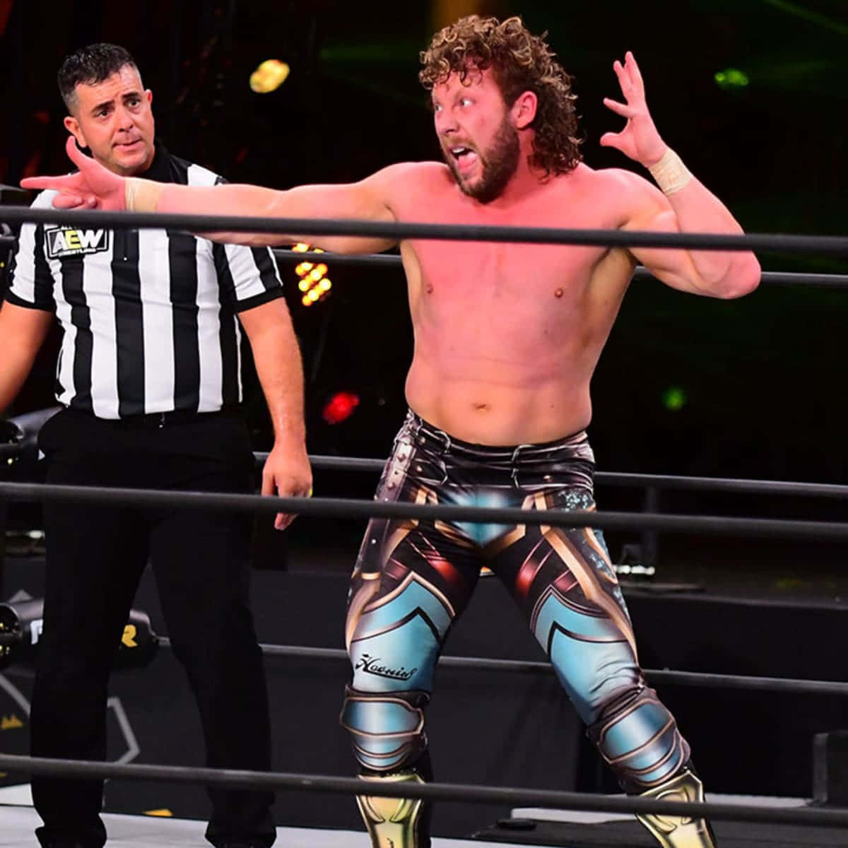 Kenny Omega, The Renowned Canadian Pro Wrestler, In A Pose With Referee Background