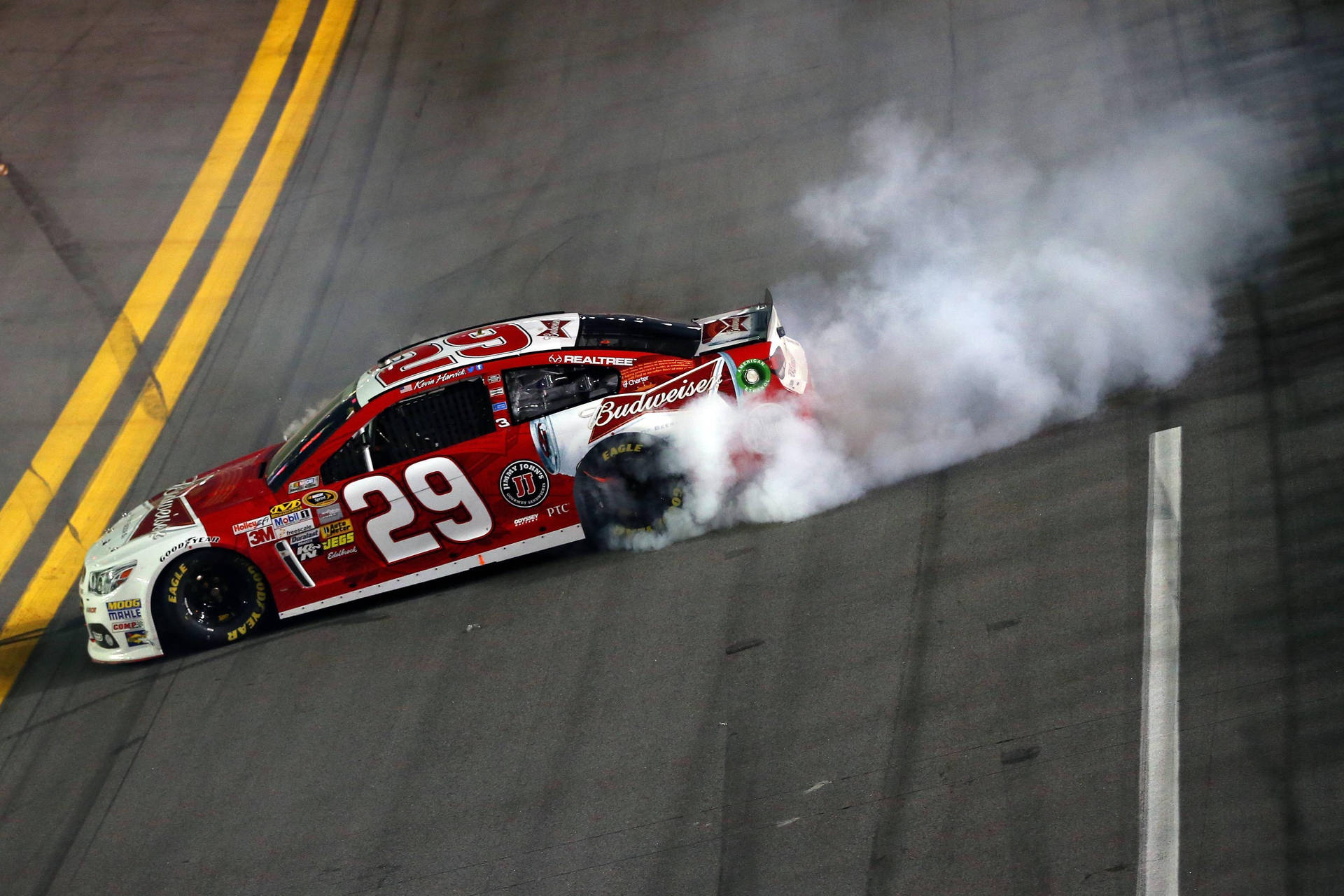 Kevin Harvick Burning Rubber On Race Track Background