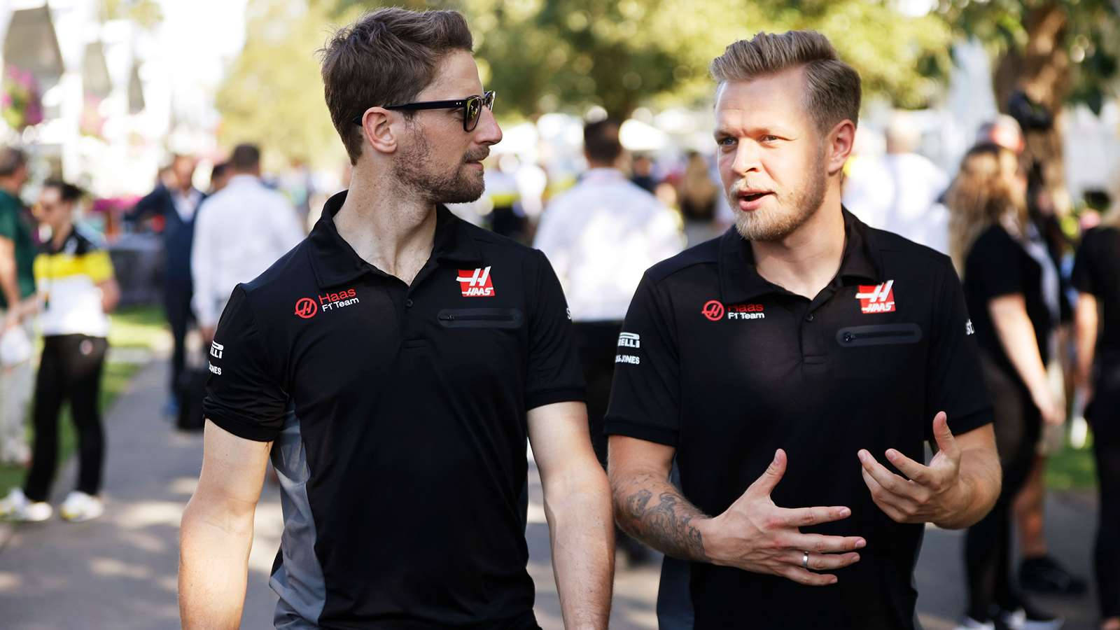 Kevin Magnussen And Romain Grosjean Deep In Conversation At A Racing Event Background