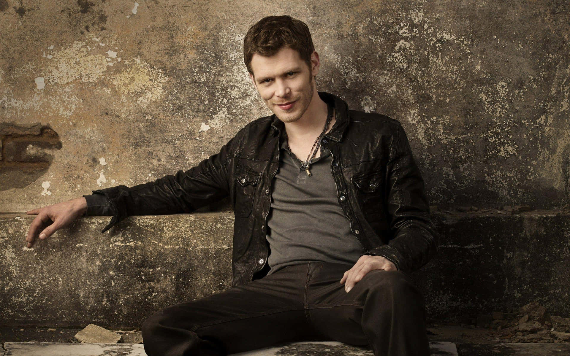 Klaus Mikaelson Sitting Against Concrete Wall Background
